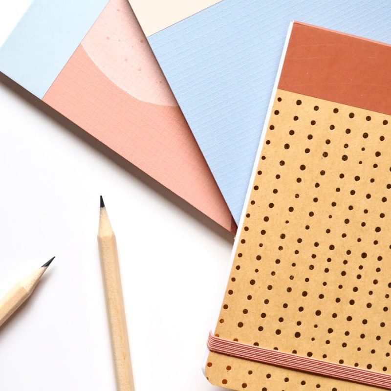 Colorful notebooks and pencils arranged neatly for a creative workspace.
